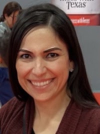 a woman smiling in front of a booth at a convention